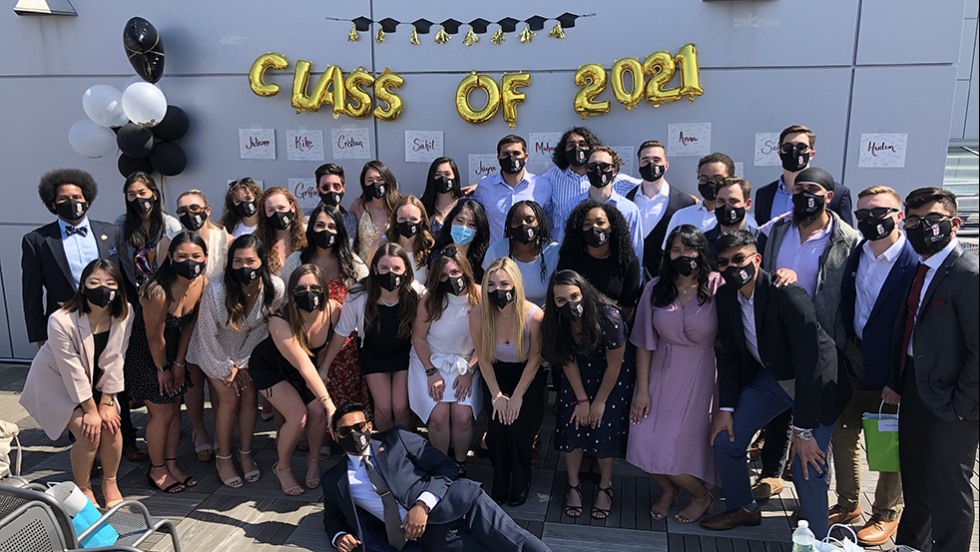 group of people posing for photo under banner that says Class of 2021